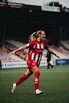Fotballspiller i rød og hvit drakt løper med hendene ut fra kroppen på en stadionbane.