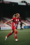 Fotballspiller i rød og hvit drakt løper med hendene ut fra kroppen på en stadionbane.