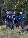 Fem turgåere står samlet med staver i en grønn skog.