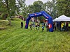 Deltakere ved en SpareBank 1-bue og telt i en grønn park.
