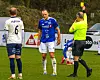 Fotballspillere og dommer på en gressbane under kamp.
