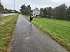 Løper på våt asfaltvei i et grønt, landlig landskap.