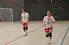 To håndballspillere på en innendørsbane mot kameraet.