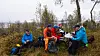 En gruppe turgåere sitter samlet i en høstlig skog.