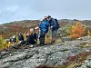 Turgåere tar pause på en steinete fjellrygg i høstlandskap.