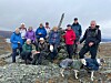 Turgruppe og hund på et steinete fjellplatå under overskyet himmel.