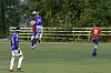 Tre fotballspillere i blå og røde drakter på en gressbane.