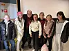 Gruppe mennesker står samlet innendørs foran en lys vegg.