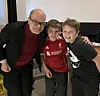 Tre personer smiler til kameraet; en gutt har på seg rød Liverpool-drakt.