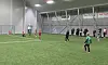 Barn spiller fotball på kunstgress i en innendørshall.