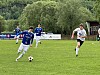 Fotballspiller i blå drakt fører ballen foran motspillere i hvitt på en gressbane.
