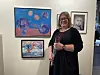Kvinne med en rose foran kunstverk på en gallerivegg.
