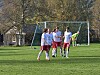 Fotballspillere i hvitt og rødt trener på en gressbane foran et mål.