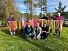 Gruppe personer viser fargerike håndlagde tekstiler utendørs i en park.