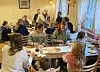Flere gjester spiser sammen rundt bord i en lys restaurant.