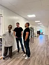 Tre personer snakker sammen i en lys kontorgang.