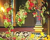 Fargerik blomsterdekorasjon foran et utsmykket interiør med mørkt treverk og gullfargede detaljer.
