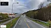 Asfaltert landevei med veimerking, autovern og skog på begge sider.