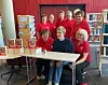 Gruppe personer poserer ved et bord med bøker i et bibliotek eller en bokhandel.