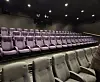 Tomt auditorium med rader av lilla og grå seter under dempet belysning.