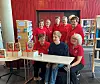 En gruppe mennesker poserer rundt et bord med bøker foran bokhyller.