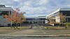 Moderne bygningskompleks med høsttrær, åpen plass og skyet himmel.