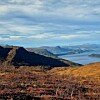 Fargerikt fjellterreng med fjell, fjord og blågrå himmel.