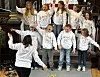 Barn i hvite gensere synger i koret i en kirke mens en dirigent leder dem.