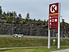 Circle K-skilt ved landevei med fjellskjæring, skog og biler.