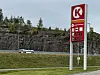 Circle K-skilt ved landevei med fjellskjæring, skog og biler.