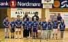 Ungdomslag i blå håndballdrakter poserer på en innendørs bane.
