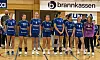 Ungdomsspillere i blå håndballdrakter står på banen foran en tribune.