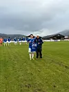 Fotballspiller og trener viser drakt nummer 200 på en bane.