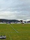 Fotballspillere på en gressbane med ballen i spill og drikkeflasker i forgrunnen.