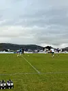 Fotballspillere på en gressbane med ballen i spill og drikkeflasker i forgrunnen.
