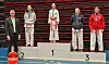 Fem medaljevinnere står på en seierspall under en idrettsseremoni.