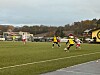Fotballspillere i gule og hvite drakter kjemper om ballen på en grønn bane.