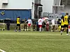 Fotballspillere i gule, svarte og røde drakter på en kunstgressbane.