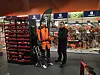 En ansatt står foran hyller med verktøy i en butikk med en motorsag.
