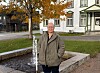 Person står ved en fontene på et torg med høsttrær og eldre bygninger.