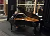 Pianist spiller på et svart flygel i et moderne lokale.
