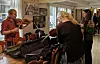 Kvinne spiller fiolin i en butikk mens en annen ser på instrumentkasser.