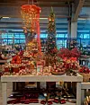 Juleutstilling med pyntet tre, røde dekorasjoner og gaveartikler på et bord.
