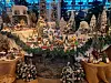 Detaljrik juleutstilling med miniatyrhus, figurer, trær og vinterlandskap.