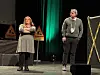 To skuespillere på en teaterscene med grønne lys og varselskilt.